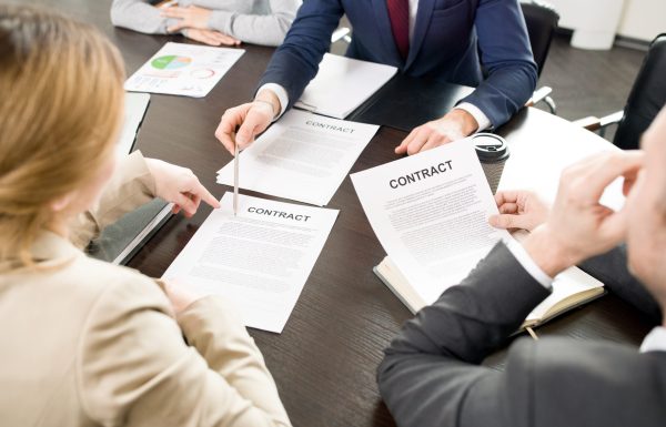 Close-up of business people discussing contract conditions: unrecognizable male manager pointing at text and explaining information to business partner at meeting